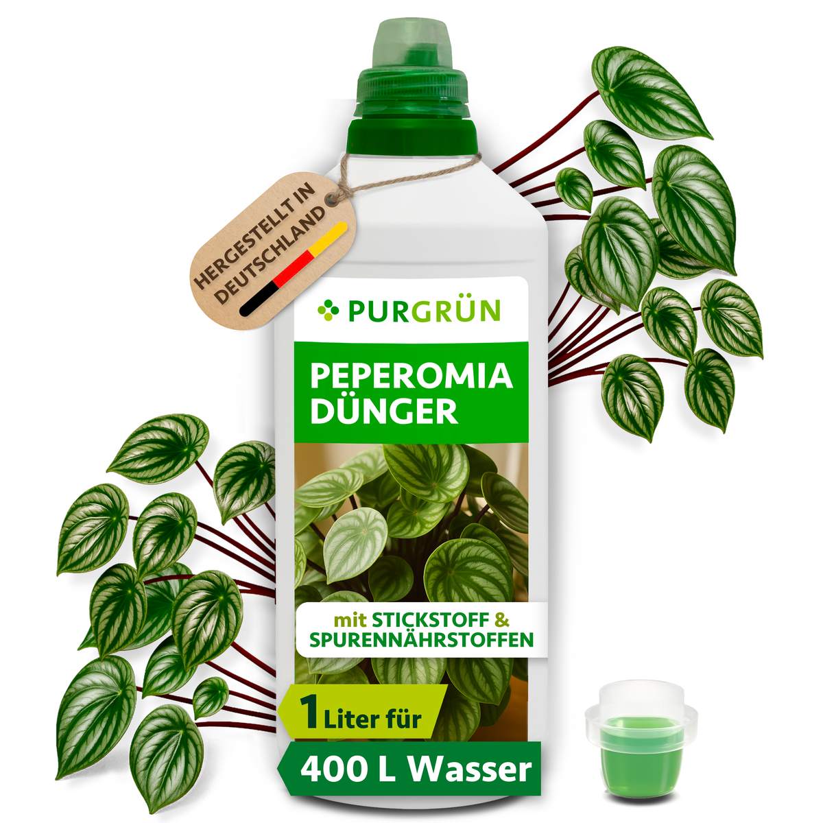 Purgrün Peperomia-Dünger in der 1-Liter-Flasche mit Dosierkappe, umgeben von Peperomia-Blättern und mit Anhänger „Hergestellt in Deutschland“.