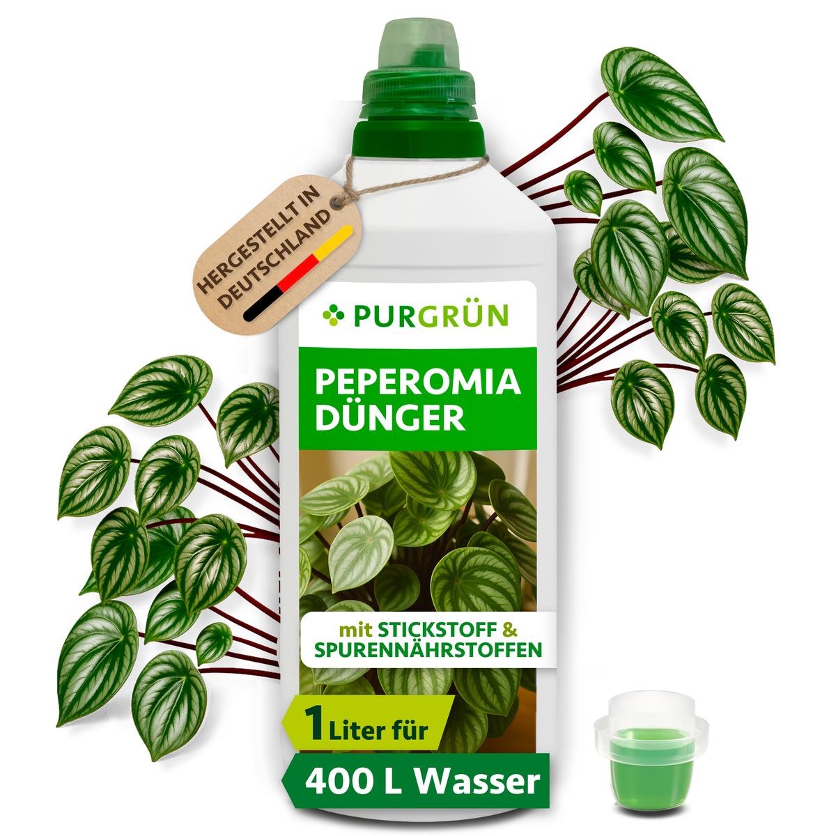Purgrün Peperomia-Dünger in der 1-Liter-Flasche mit Dosierkappe, umgeben von Peperomia-Blättern und mit Anhänger „Hergestellt in Deutschland“.
