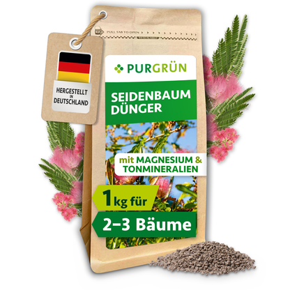 Purgrün Seidenbaum-Dünger, 1 kg, mit Magnesium und Tonmineralien, umgeben von rosa Seidenbaumblüten und Granulat.